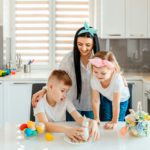 Children with mom make decorations for Easter while sitting at the kitchen table