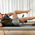 Fit man doing crisscross crunches during training on pilates machine
