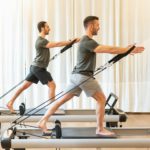 Fit men exercising on pilates machines in gym