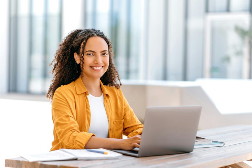 Photo of a successful curly haired girl, brazilian or hispanic nationality, outsourcing employee or