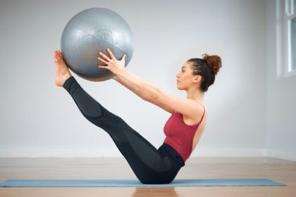 Pilates can be challenging. Shot of a young woman doing core exercises using a medicine ball.