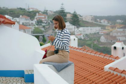 Tourist checking social media at mediterranean cityscape. Smiling travel blogger