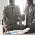 Two african american businessman at work in the office looking at the documents