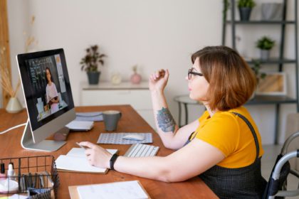 Young disable teacher or educational consultant in wheelchair sitting by desk